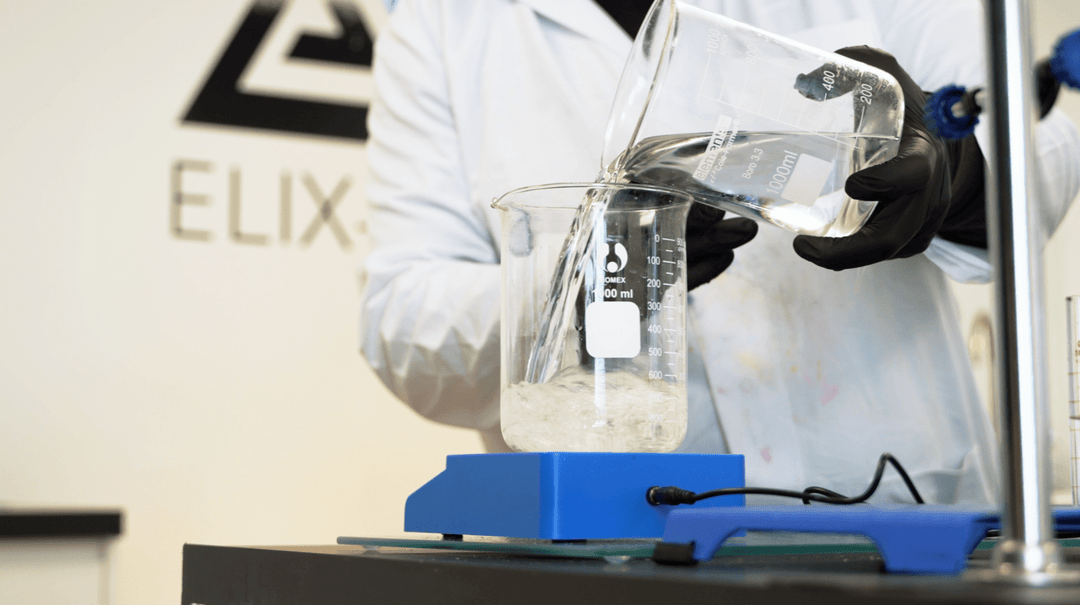 Chemist manufacturing fragrances mixing raw materials to make scent in laboratory setting